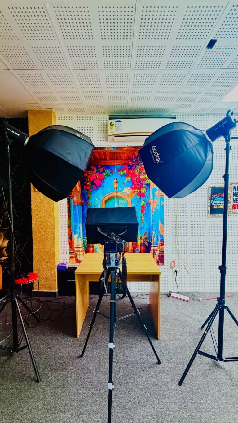 Professional podcast studio setup with microphones, studio lighting, camera equipment, and recording workspace for content creation and live streaming.
